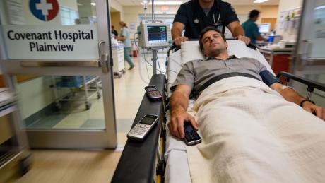 Plainview Man Sues Covenant Health Over Staffer's "One For the Hoes" Jab (AI-generated image of man entering ER with 3 cell phones)